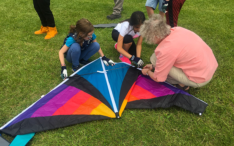 Students and teacher assembling kite in the field
