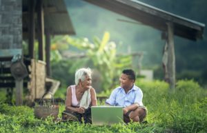 Grandmother and grandson looking at a laptop computer together on a farm.