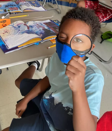 Image of a young boy looking up with a magnifying glass