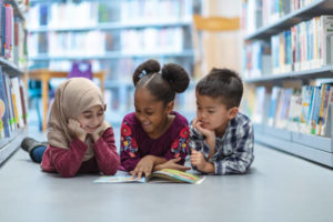 Image of young students reading together on the floor of a library